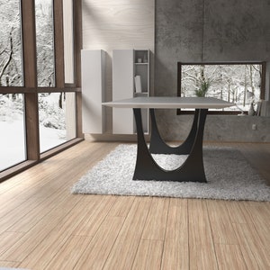 May include: A modern dining table with a white top and black, curved legs. The table is set in a room with large windows overlooking a snowy landscape.