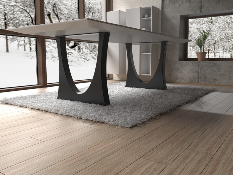 May include: A modern white dining table with a black metal base. The table is set on a white shag rug in a room with large windows and wooden floors.