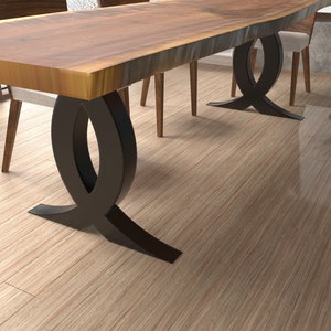 Puede incluir: Una mesa de comedor de madera con una tapa de borde vivo y dos patas de metal negro. Las patas tienen forma de ocho.