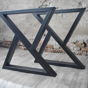 May include: Two black metal table legs with a geometric, triangular design. The legs are made of thick, sturdy metal and have a matte black finish.