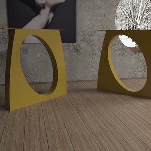 May include: Two gold metal table bases with a unique oval cutout design. The bases are on a wood floor.