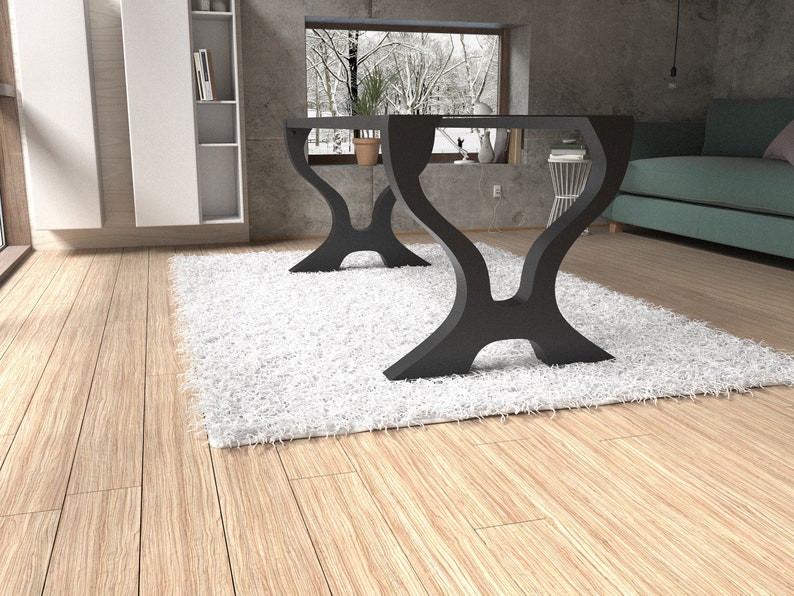 May include: Two black metal table bases with a unique Y-shaped design. The bases are on a white fluffy rug in a room with wood floors.