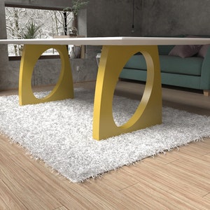 May include: A white table with a yellow, oval-shaped base. The table is sitting on a white shag rug in a room with wooden floors.