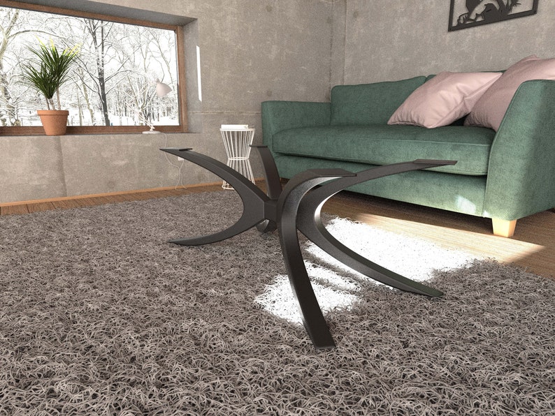 Puede incluir: Una mesa de centro de metal negro con una base &uacute;nica en forma de X curvada. La mesa est&aacute; sobre una alfombra de pelo gris en un sal&oacute;n.