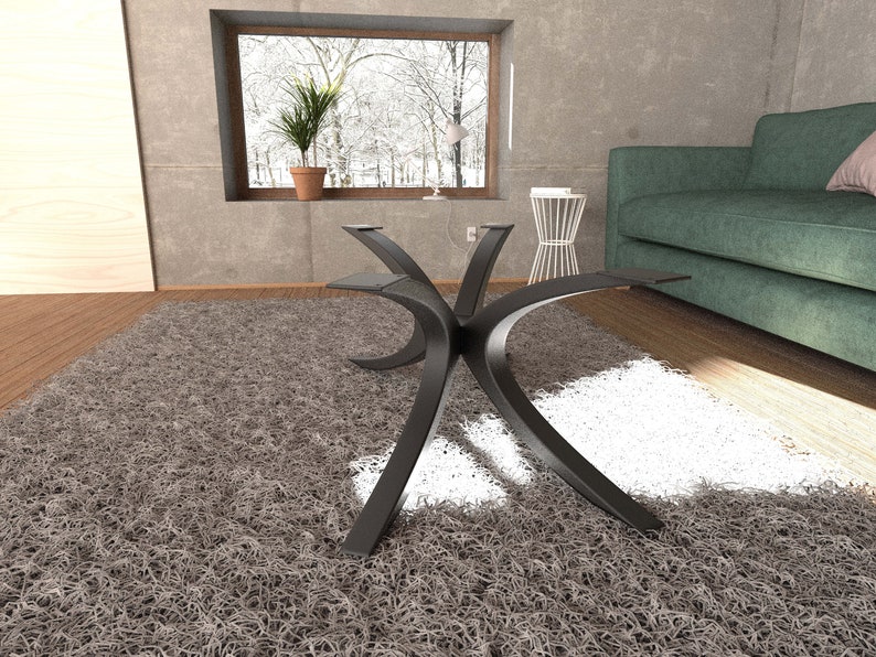 Puede incluir: Una mesa de centro de metal negro con una base curva en forma de X. La mesa est&aacute; sobre una alfombra de pelo gris en un sal&oacute;n.