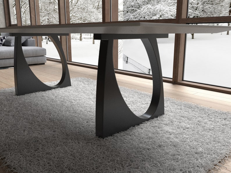 May include: A modern dining table with a gray tabletop and black metal legs. The legs have a unique curved design with a circular cutout.