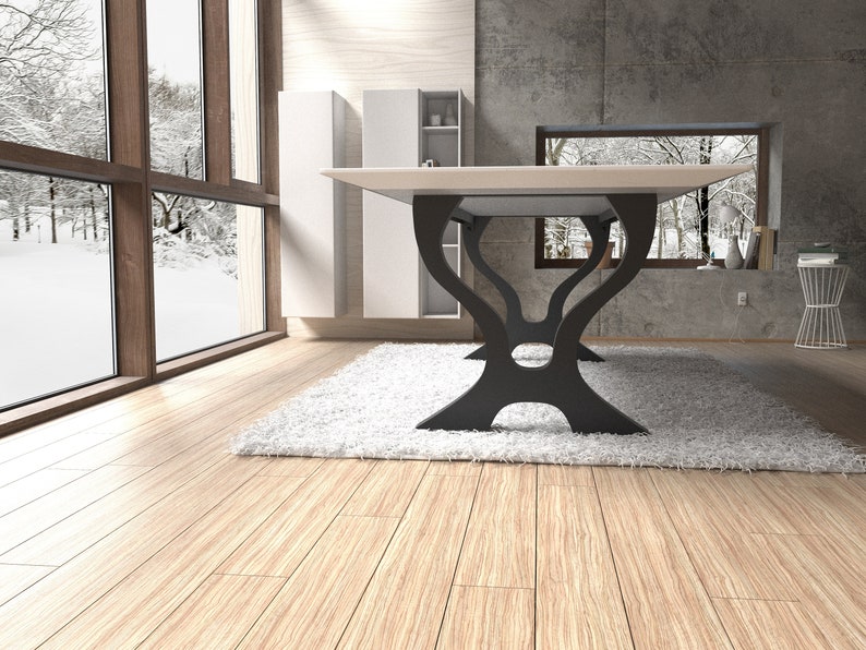 May include: A white rectangular dining table with a black, modern, abstract base. The table is in a room with large windows and a white rug.