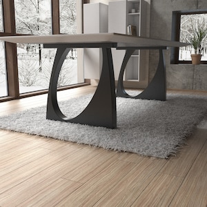 May include: A white rectangular dining table with a modern design. The table has a white top and black metal legs with a unique curved shape. The table is set on a white fluffy rug in a room with wooden floors.