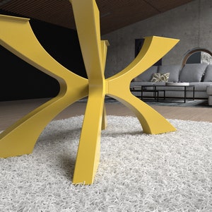May include: A modern, yellow table base with a unique, geometric design. The base features six curved legs that meet in the center, creating a star-like shape. The table base is made of a solid material and is set on a white shag rug.