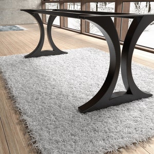 May include: A black metal table base featuring two large, curved, C-shaped supports connected by two horizontal bars at the top. The structure has a smooth, matte finish and a wide, stable footprint designed to support a tabletop surface.
