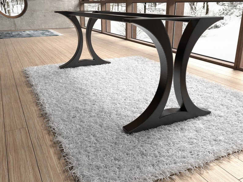 May include: A black metal table base featuring two large, curved, C-shaped supports connected by two horizontal bars at the top. The structure has a smooth, matte finish and a wide, stable footprint designed to support a tabletop surface.