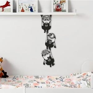 May include: Black and white wall decal of three Minions characters hanging from a rope. The Minions are in a line, with the largest Minion at the top and the smallest Minion at the bottom.