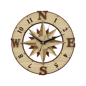Puede incluir: Un reloj de pared de madera con un diseño de rosa de los vientos. La esfera del reloj es de color marrón claro con números y puntos cardinales en marrón oscuro. Las manecillas son negras. El reloj mide unos 30 cm de diámetro.