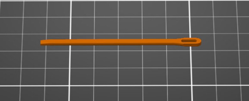 Puede incluir: Una aguja de pl&aacute;stico naranja, larga y recta, con una punta plana y roma en un extremo y un ojo alargado en el otro, colocada horizontalmente sobre un fondo de cuadr&iacute;cula gris oscuro con l&iacute;neas blancas.