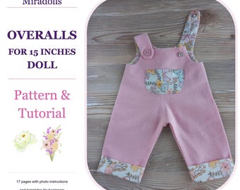 Op de afbeelding: Roze tuinbroek voor een pop van 38 cm, met een bloemenpatroon op de zak, boorden en schouderbanden. Het kledingstuk heeft knopen op de banden. De tekst luidt Miradolls, OVERALLS FOR 15 INCHES DOLL, Pattern & Tutorial, 17 pagina's met instructies.