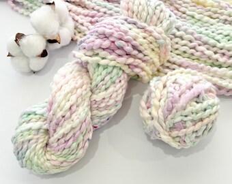 Può includere: Un gomitolo di filato grosso dai colori pastello con una pallina di filato abbinata e due batuffoli di cotone. Il filato è un mix di bianco, rosa, verde e giallo. Il filato è spesso e strutturato, perfetto per progetti di maglia o uncinetto.