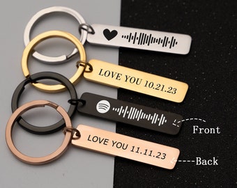 Könnte beinhalten: Vier silberne Schlüsselanhänger mit schwarzer, goldener und roségoldener Oberfläche. Jeder Schlüsselanhänger hat ein rechteckiges Schild mit einem einzigartigen Design und dem Text "LOVE YOU" gefolgt von einem Datum. Die Vorderseite des Schildes zeigt ein Spotify-Logo und einen Barcode, während die Rückseite ein Herz und einen Barcode zeigt.