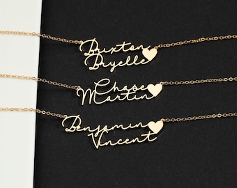 May include: Three gold-toned necklaces, each featuring two names written in a cursive script font stacked vertically, with a small heart icon positioned to the right of the top name. The names displayed are Brixton and Bryelle, Chase and Martin, and Benjamin and Vincent.