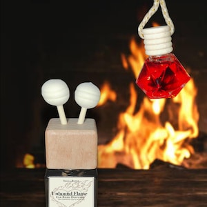 May include: A car reed diffuser set featuring a square glass bottle with a wooden cap and two white spherical reed sticks, and a hanging diamond-shaped glass bottle filled with red liquid, suspended by a white cord with a wooden bead.