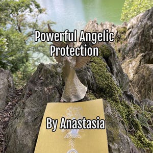 May include: A golden angel figurine with outstretched wings stands on a rock, with the text "Powerful Angelic Protection" above and "By Anastasia" below. A golden card with a design is in front of the angel. The background shows a lake and trees.