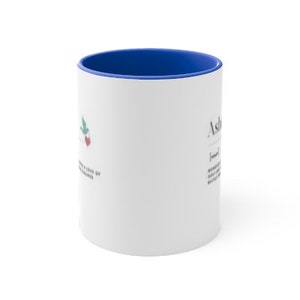 Op de afbeelding: Witte keramische mok met een blauwe rand. De mok heeft een groen vogeltje met een rood hartje en het woord "Ashley" met een definitie.