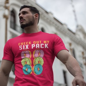 May include: Red t-shirt with the text "CHECK OUT MY SIX PACK" and a graphic of six colourful doughnuts.