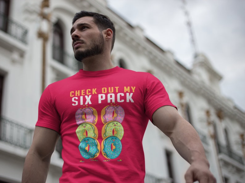 May include: Red t-shirt with the text "CHECK OUT MY SIX PACK" and a graphic of six colourful doughnuts.