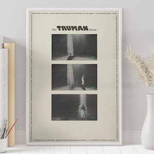 May include: A black and white poster for the film "The Truman Show" featuring three scenes from the film. The poster has the title "the TRUMAN show" in large, bold letters. The scenes show Truman Burbank walking towards a waterfall in a studio setting.