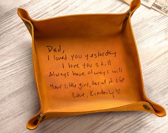 May include: A square camel-colored leather valet tray with brass-toned corner snaps. The interior features black engraved handwriting that reads: Dad, I loved you yesterday, I love you still, Always have, always will, Your little girl, for all of life, Love, Kimberly.