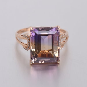 May include: A rose gold ring with a large, square-shaped amethyst gemstone. The gemstone is a gradient of purple, yellow, and brown. The ring is accented with small diamonds.