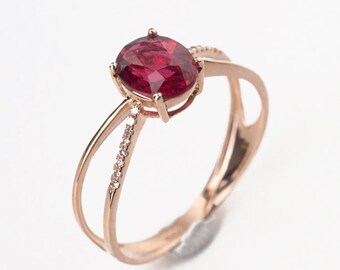 Könnte beinhalten: Ein Ring aus Roségold mit einem großen ovalen Rubin und einem Band, das mit kleinen Diamanten besetzt ist.