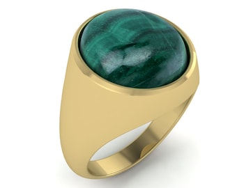 May include: A gold ring featuring a large, oval-shaped malachite stone. The malachite is a deep green color with swirling patterns. The ring has a smooth, polished gold band.