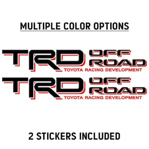 Op de afbeelding: Twee zwarte en rode TRD Off Road Toyota Racing Development stickers. De stickers hebben de tekst "MULTIPLE COLOR OPTIONS" en "2 STICKERS INCLUDED" in zwarte letters.