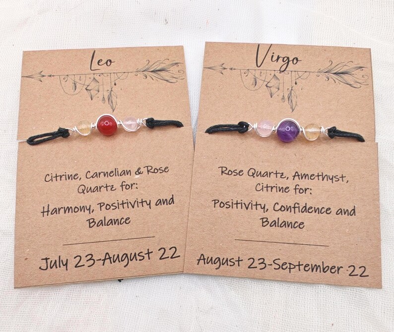 May include: Two handmade gemstone bracelets on display. One features citrine, carnelian, and rose quartz, while the other showcases rose quartz, amethyst, and citrine. Each bracelet is on a card with the zodiac sign and associated traits.