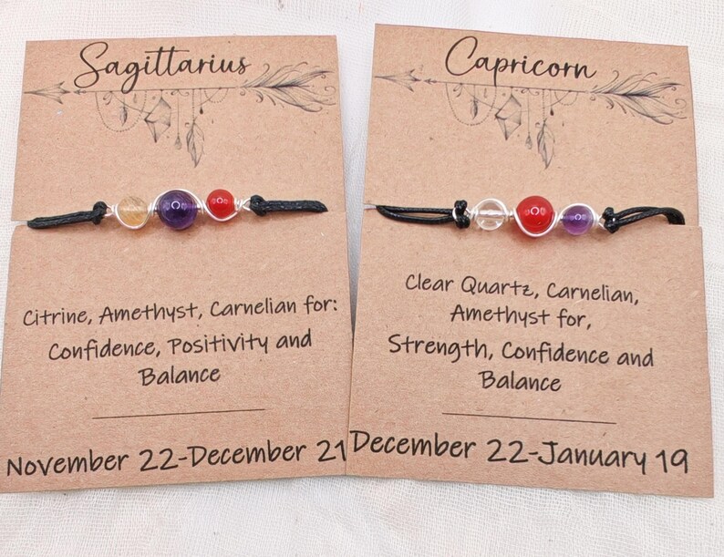 May include: Two gemstone bracelets on cards. One reads "Sagittarius" with citrine, amethyst, and carnelian beads. The other reads "Capricorn" with clear quartz, carnelian, and amethyst beads. Each card has text about the stones' properties.