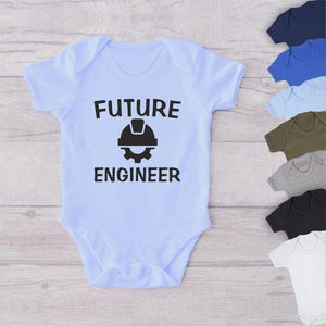 May include: Light blue baby onesie with black text that reads "FUTURE ENGINEER" and a black graphic of a hard hat and gear.