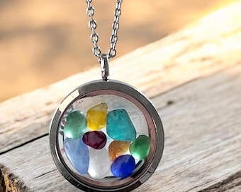 May include: A silver-toned necklace with a round pendant filled with colorful, polished stones. The stones are various colors, including blue, green, yellow, and red. The pendant hangs from a delicate chain, creating a simple yet eye-catching accessory.
