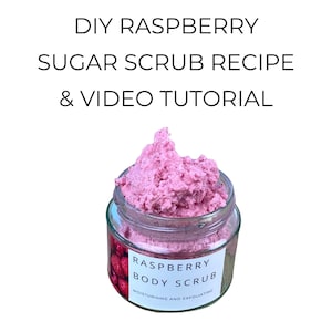 Könnte beinhalten: Ein Glas mit pinkfarbenem Himbeer-Körperpeeling. Das Glas hat ein weißes Etikett mit der Aufschrift "Raspberry Body Scrub" und wird als feuchtigkeitsspendend und peelend beschrieben. Der Text "DIY Raspberry Sugar Scrub Recipe & Video Tutorial" steht oben.