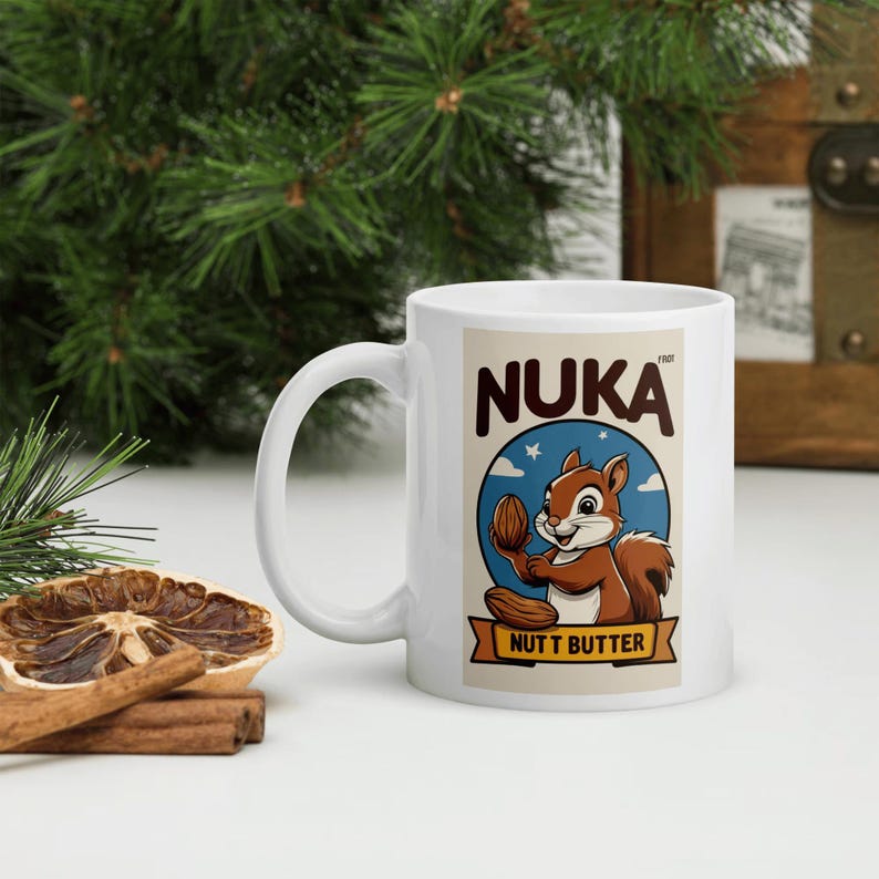 May include: A white ceramic mug with a black handle and the text "But first, coffee" in a handwritten style. The mug is on a white surface. The mug is approximately 4 inches tall.