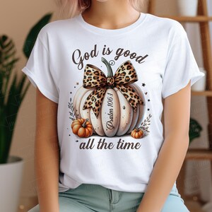 May include: White t-shirt with a brown and white pumpkin design. The pumpkin has a leopard print bow and the text "God is good Psalm 106:1 all the time".