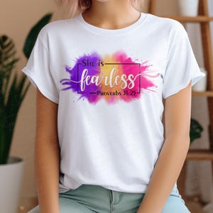 May include: White t-shirt with a colourful watercolour design and the text "She is fearless - Proverbs 31:25"