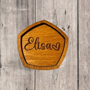 May include: A wooden coaster with a heart and the name "Elisa" engraved on it.
