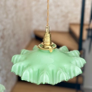 May include: A green glass pendant light with a ruffled edge and a brass fixture.
