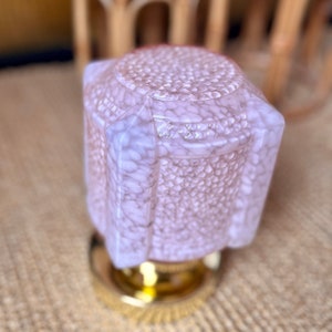 May include: A pink glass lampshade with a textured surface. The lampshade is octagonal in shape and has a gold metal base.