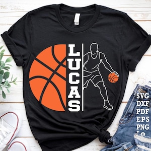 Peut inclure: T-shirt noir avec un motif de basket-ball. Le motif comprend la moitié d'un ballon de basket-ball orange, le nom "LUCAS" en blanc et un contour blanc d'un joueur de basket-ball dribblant un ballon. Vêtement de sport.