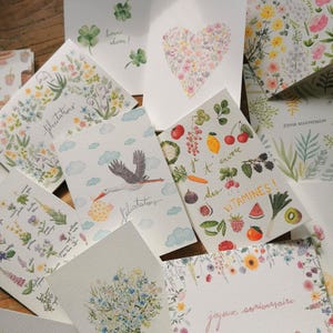 Peut inclure: Un assortiment de cartes de vœux à l'aquarelle avec des motifs floraux et naturels. Les cartes présentent des images de fleurs, un cœur, une cigogne portant un bébé et divers fruits et légumes. Certaines cartes ont du texte en français.