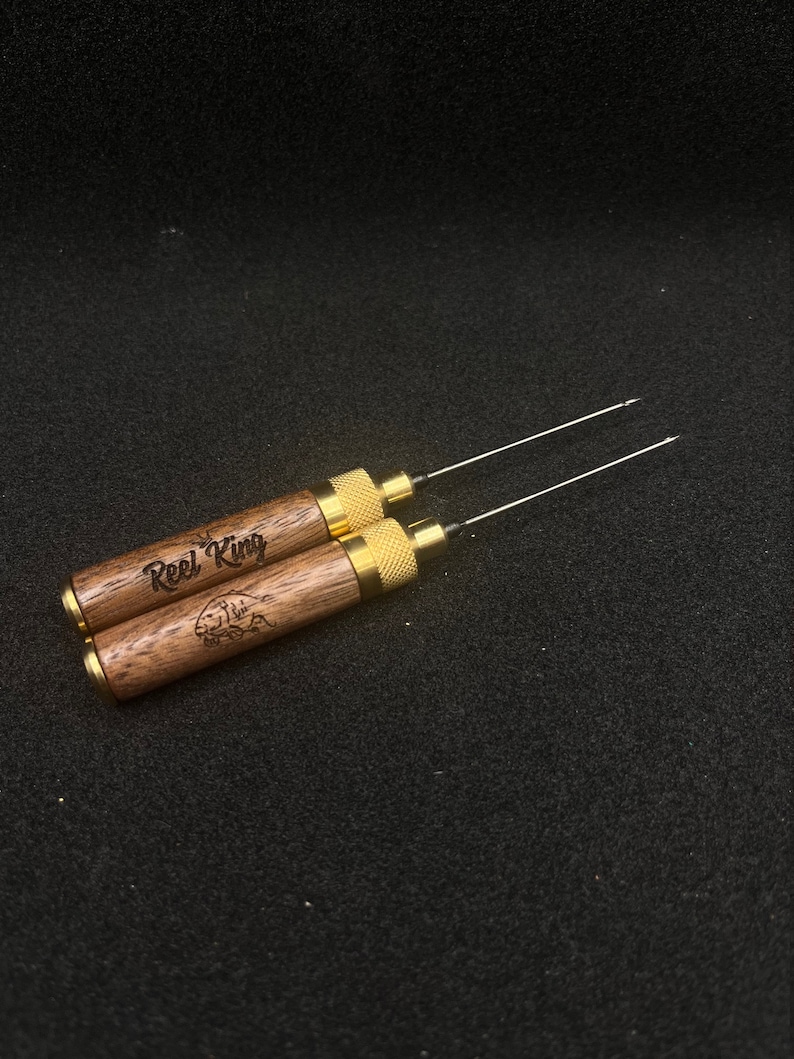 May include: Two wooden tools with gold metal tips and a brown wood handle. The handle is engraved with the words "Reel King" and a fish graphic.