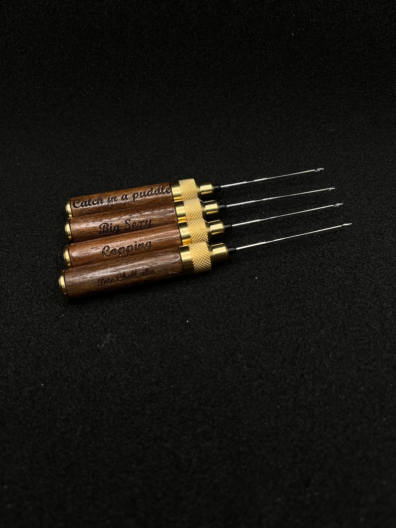 May include: Five wooden tools with gold metal accents and engraved text. The text reads "Catch in a puddle", "Big Sexy", "Copping", and "Pete Chocolata".