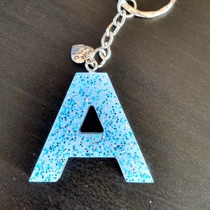 May include: A blue glitter letter A keychain with a silver charm that says "Made with love".