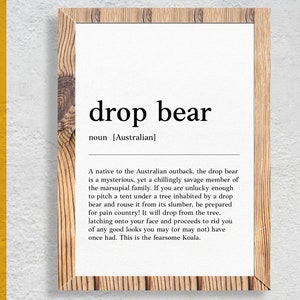 May include: A white framed print with a black and white definition of the term "drop bear" in Australian English. The definition describes the drop bear as a mysterious and savage marsupial that can be found in the Australian outback.